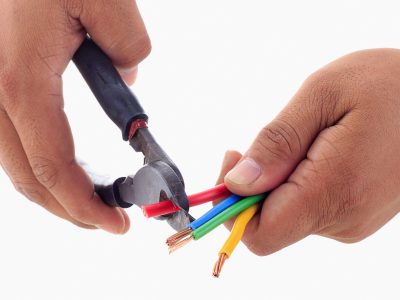 Hand hold cutter to strip red cable. Isolated white background.